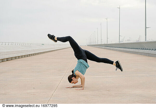 sporty girl doing a handstand while dancing in the street