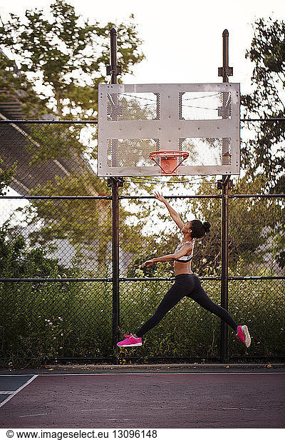 Sporty woman reaching basketball hoop