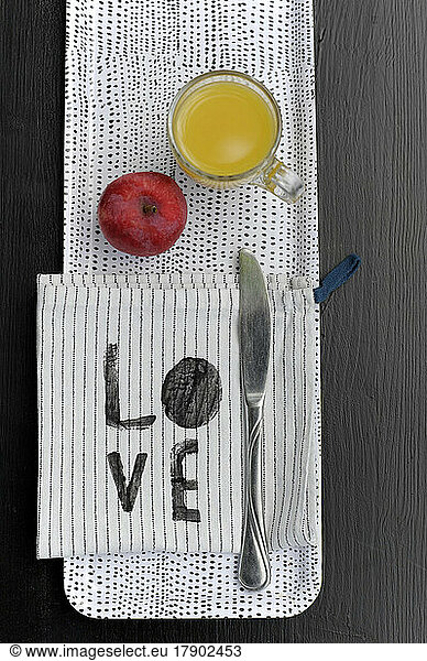 Spotted tray with apple  glass of orange juice  dish towel and table knife