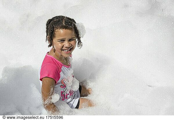 St. Paul  Minnesota. 5 year old bi-racial girl having fun in the Como Town foam pit at the park.