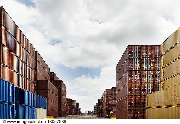 Stack of cargo containers at commercial dock against cloudy sky