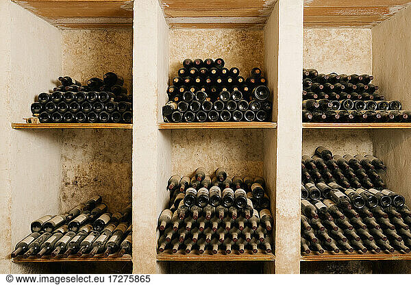 Stack of old wine bottles in rack at cellar
