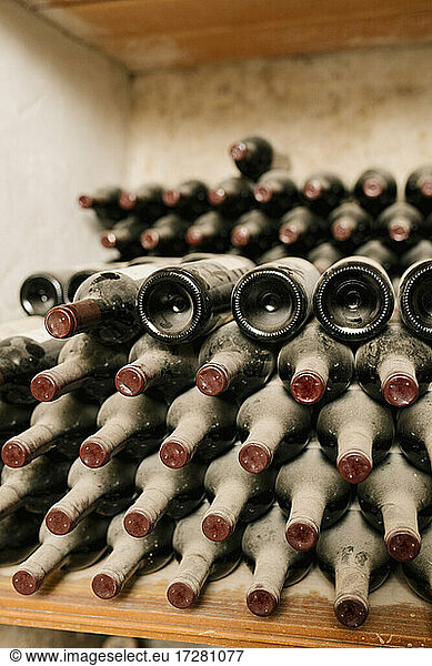 Stack of old wine bottles with dust at cellar