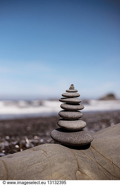 Stack of stones on rock against blue sky