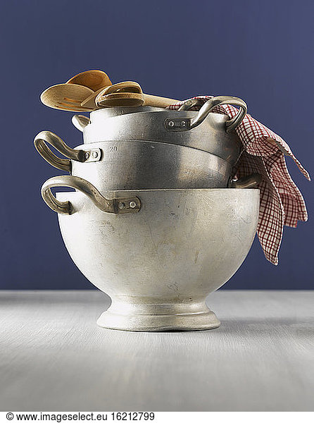 Stacked aluminium pots  wooden spoons and dishcloth