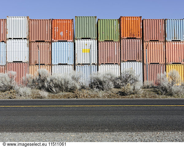 Stacks of colourful shipping containers beside a road.