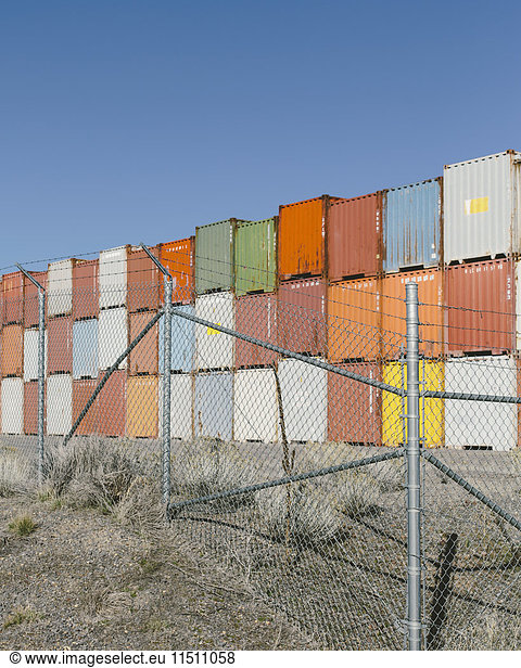 Stacks of colourful shipping containers  fence in foreground  Nevada  USA.