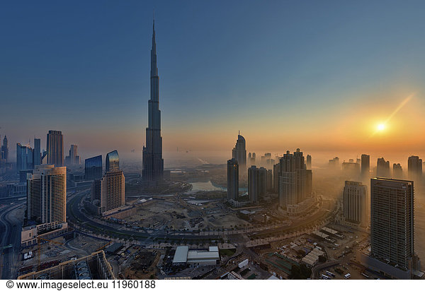 Stadtbild von Dubai  Vereinigte Arabische Emirate in der Abenddämmerung  mit dem Wolkenkratzer Burj Khalifa und anderen Gebäuden im Vordergrund.