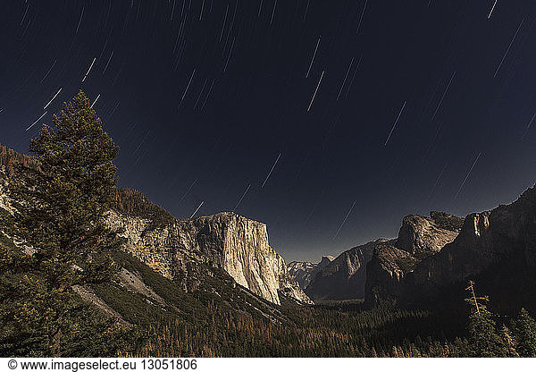 Star trails against rocky mountains