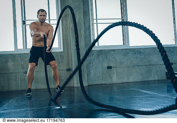 Starker Mann beim Training mit dem Seil im Functional Training Fitness.