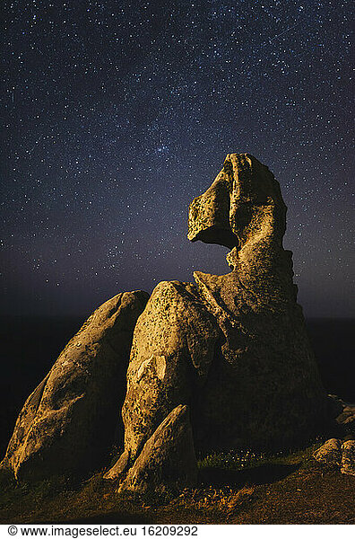 Starry night sky over small rock formation