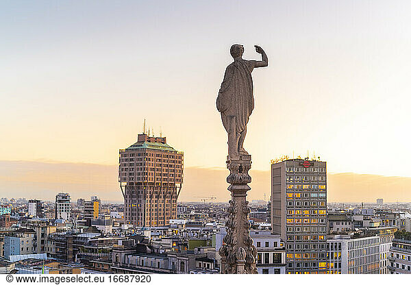 Statue from the top of the Cathedral in Milan with the Torre Velasca in the background before the sunset