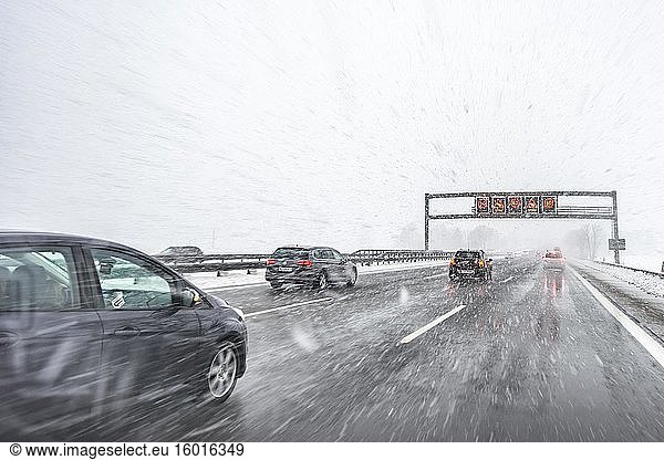 Staugefahr und Geschwindigkeitsbegrenzung  schlechtes Wetter  Autoverkehr bei starkem Schneefall und Regen auf der Autobahn A8  bei München  Bayern  Deutschland  Europa