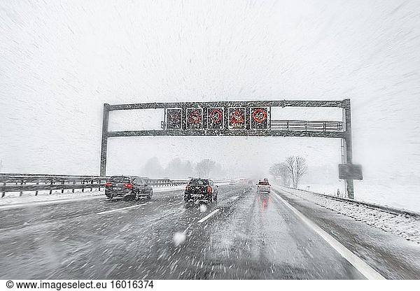 Staugefahr und Geschwindigkeitsbegrenzung  schlechtes Wetter  Autoverkehr bei starkem Schneefall und Regen auf der Autobahn A8  bei München  Bayern  Deutschland  Europa