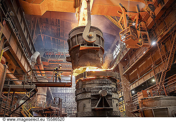 Steelworker starting molten steel pour in steelworks