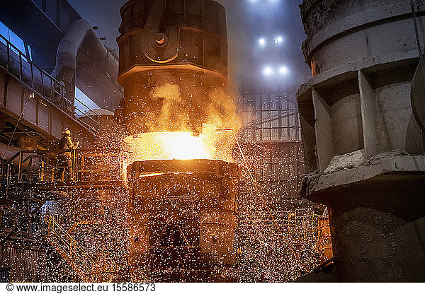 Steelworkers starting pour of molten steel in steelworks