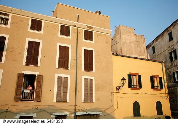 stehend Frau Fenster Wand Wohnhaus Großstadt vorwärts bauen Alghero Italien Sardinien