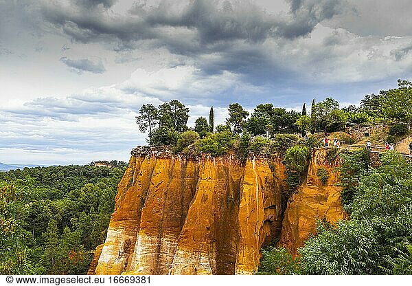 Steilabfallende Felsen im Naturpark der Ockerfelsen  darüber dramatische Wolken  Roussillon  Luberon  Provence  Frankreich  Europa