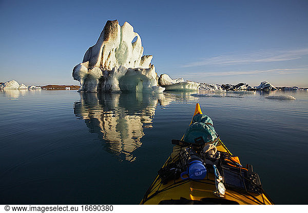 stern of a sea kayak floating towards an iceberg on a glacier lagoon