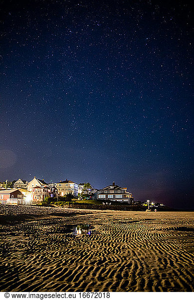 Sterne am Nachthimmel über den Strandhäusern bei Ebbe.