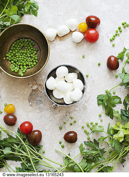 Still life of bowls of mozzarella cheese and peas with tomatoes and parsley
