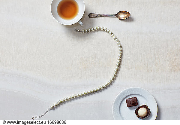 Still life of necklace  tea cup  chocolates