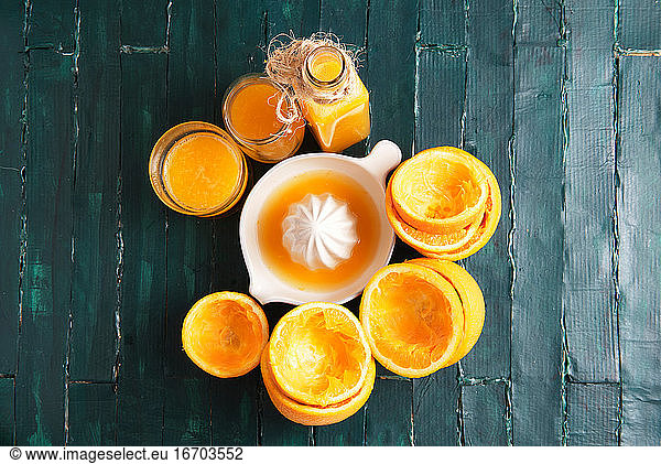 still life on a green wooden base of an orange squeezer with orange ju