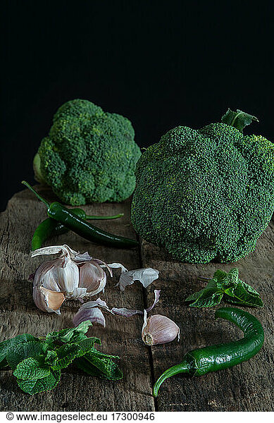 Still life with green broccoli  chiles  garlic and mint on wood board
