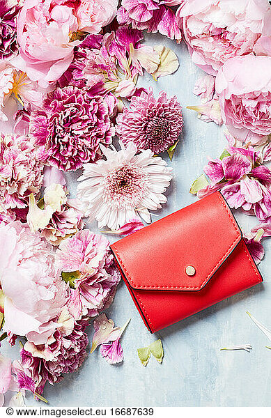 Stilleben mit roter Handtasche und Blütenblättern