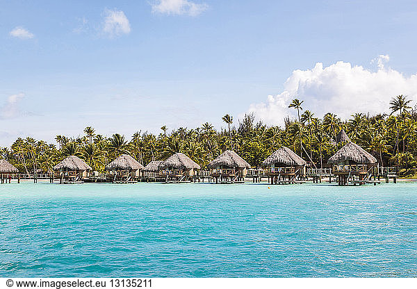 Stilt houses in lagoon of Bora Bora island against sky