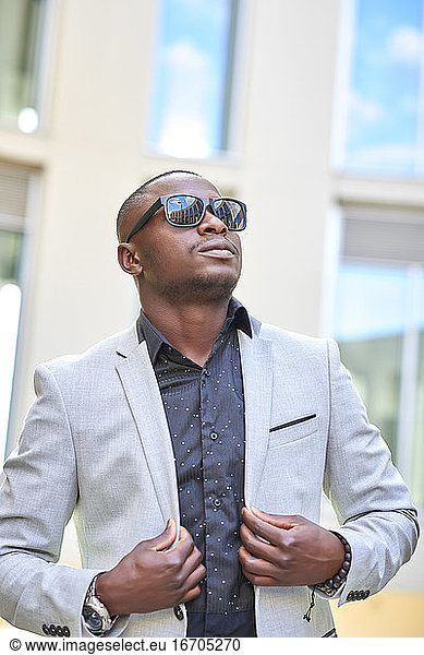 Stilvoller afroamerikanischer Geschäftsmann posiert mit Sonnenbrille.
