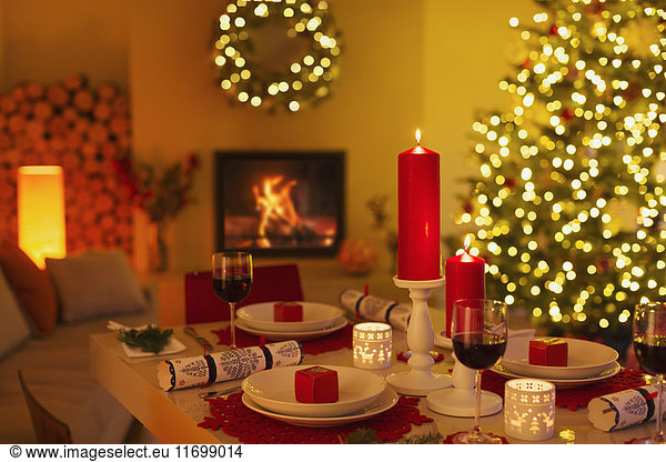 Stimmungsvolle Kerzen und Weihnachtsgebäck auf dem Esstisch im Wohnzimmer mit Kamin und Weihnachtsbaum