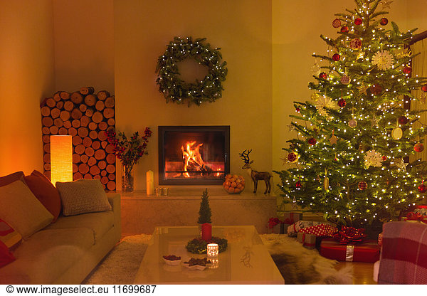 Stimmungsvoller Kamin und Kerzen im Wohnzimmer mit Weihnachtsbaum