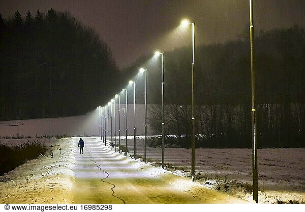 Stockholm  Schweden Ein Mann geht auf einem verschneiten  beleuchteten Weg im Vorort Huddinge.