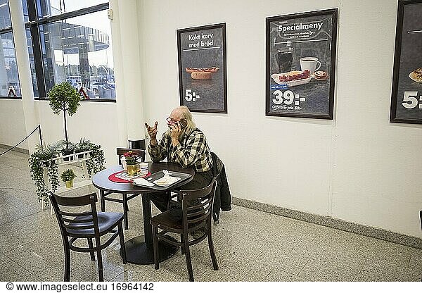 Stockholm  Schweden Ein Mann sitzt in der Cafeteria eines Einkaufszentrums  telefoniert und trinkt einen Kaffee.