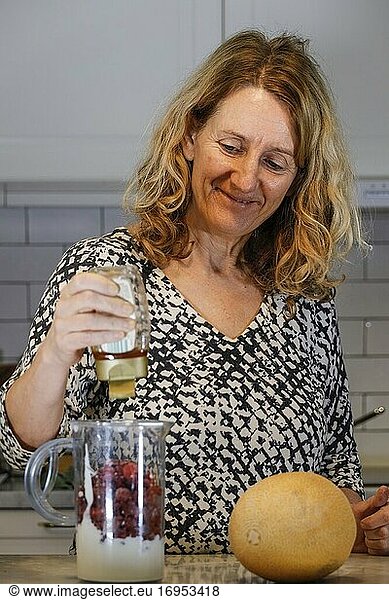 Stockholm  Schweden Eine Frau mittleren Alters bereitet auf dem Küchentisch einen Smoothie zu.