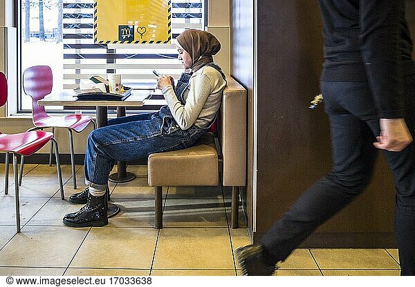 Stockholm  Schweden Eine muslimische Frau mit Kopftuch sitzt in einem McDonalds-Restaurant.