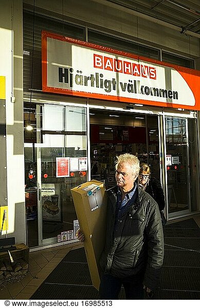Stockholm  Sweden A man exits a hardware store carrying a package and a sign in Swedish saying 'Welcome back. '.