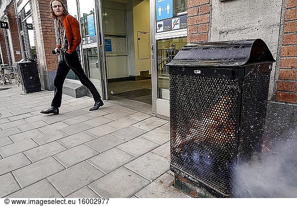 Stockholm  Sweden A pedestrian walks by a burning garbage can at the entrance to the Hornstull subway or Tunnelbana station.