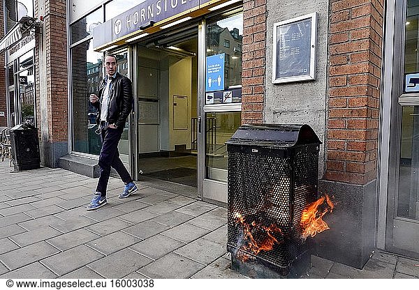 Stockholm  Sweden A pedestrian walks by a burning garbage can at the entrance to the Hornstull subway or Tunnelbana station.