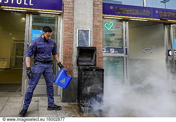 Stockholm  Sweden A security guard extinguishes a burning garbage can at the entrance to the Hornstull subway or Tunnelbana station with a bucket of water.