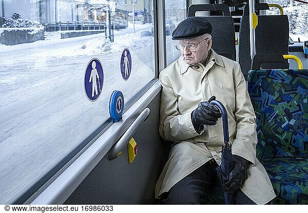 Stockholm  Sweden A senior well-dressed man sits on a bus with an umbrella.