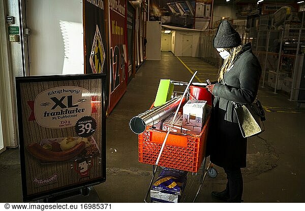 Stockholm  Sweden A woman stands at the entrance to a hardware store with DIY merchandise in a cart.