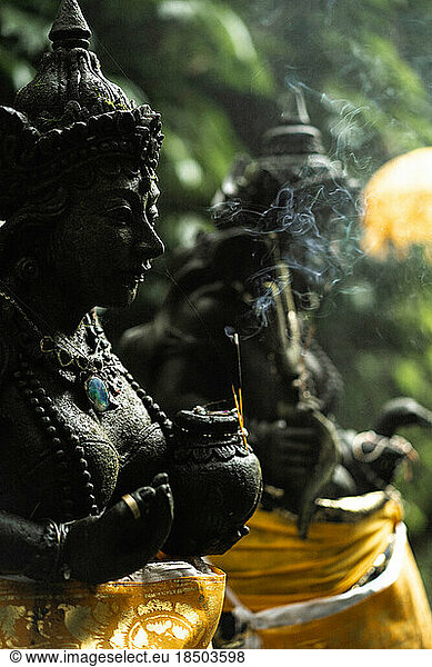 Stone statue of a Hindu god in Balinese Temple  incense smoke.