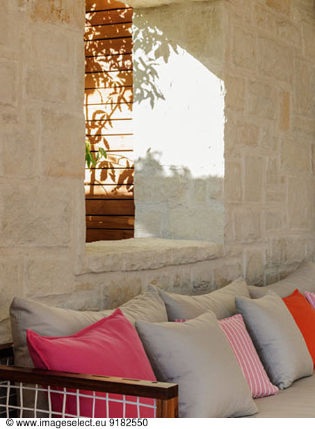 Stone wall behind patio bench with cushions