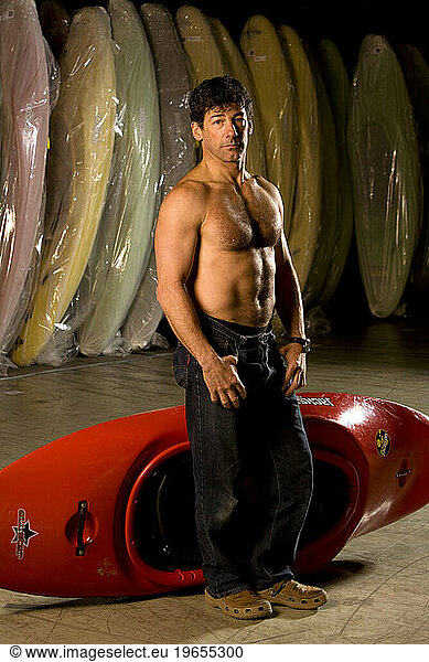 Stong attractive male kayaker without a shirt posing for a portrait with kayaks.