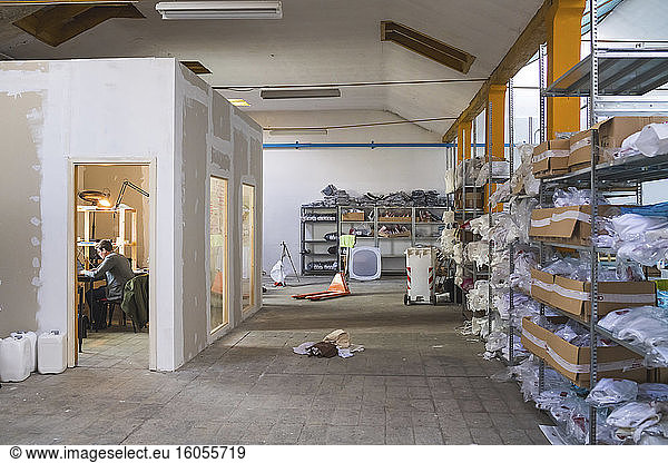 Storehouse in a factory with man working at desk in background