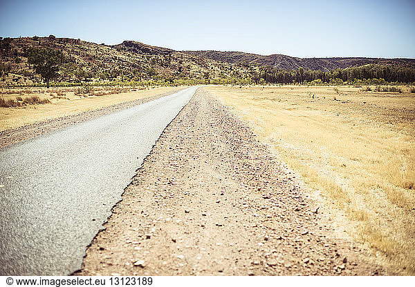 Straße inmitten der Landschaft gegen klaren Himmel in der Wüste bei Sonnenschein