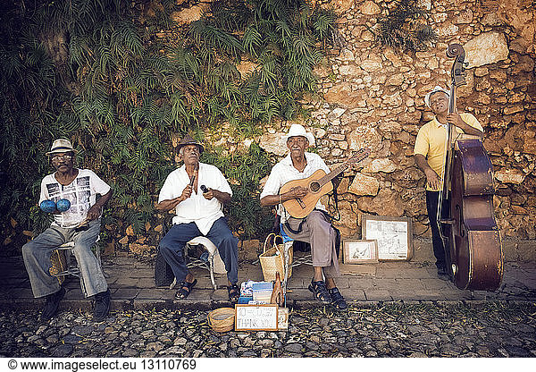 Straßenmusikanten spielen Musikinstrumente gegen eine Steinmauer