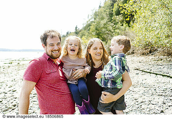 Straight on closeup portrait of a happy family of four on a sunny day